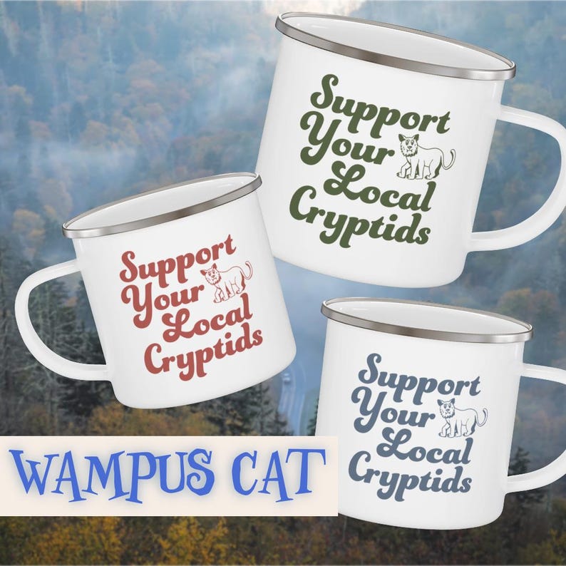 May include: Three white enamel mugs with silver rims and handles. Each mug features the text "Support Your Local Cryptids" in different colors: red, green, and blue. A cartoon cryptid is also shown on each mug. The text "Wampus Cat" is at the bottom.
