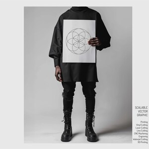 May include: A black and white geometric design on a white sheet of paper. The design is a circle with overlapping circles inside. The paper is being held by a person wearing a black shirt and black pants.