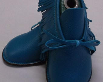 May include: A pair of teal blue leather moccasins with fringe detailing and a leather tie closure.