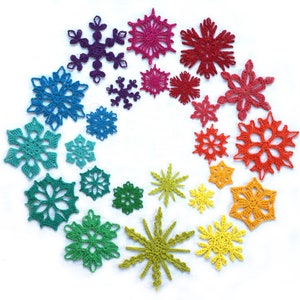 May include: A rainbow of crocheted snowflakes in various sizes, arranged in a circular pattern on a white background.