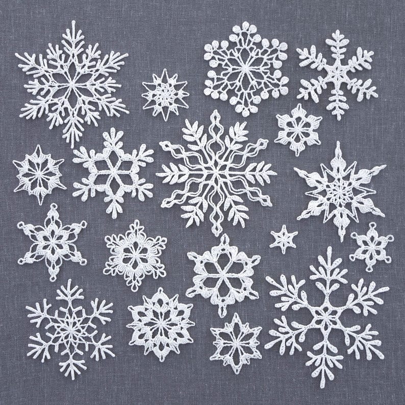 May include: A collection of 16 white crocheted snowflakes of varying sizes and designs. The snowflakes are arranged in a grid pattern on a gray fabric background.