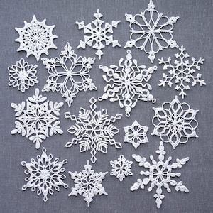 May include: A collection of white, crocheted snowflakes in various sizes and designs. The snowflakes are arranged on a gray background, showcasing intricate lace patterns and delicate details, perfect for winter crafts or decorations.