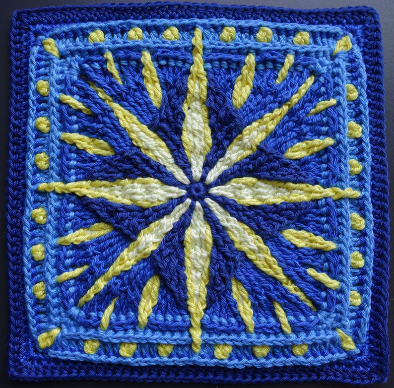 May include: A crocheted square with a blue and yellow starburst pattern. The center of the starburst is white.