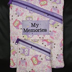 Peut inclure: Ensemble de pochettes en tissu matelassé, une grande et une petite, ornées d'un motif de hiboux roses, violets et verts. Les pochettes ont des fermetures éclair violettes et le texte "My Memories" sur un patch rectangulaire.