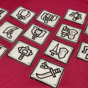 May include: Twelve white embroidered patches with black outlines on a red background. Each patch features a different weapon or tool, including a sword, axe, hammer, and shield.