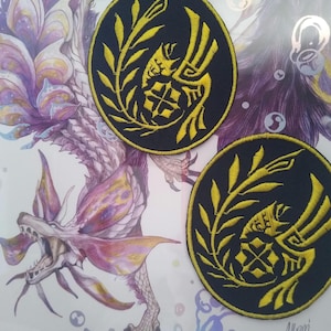 Peut inclure: Deux patchs brodés noirs et jaunes avec un motif stylisé d'un oiseau avec une couronne autour. Les patchs sont circulaires et ont un fond noir avec des broderies jaunes.