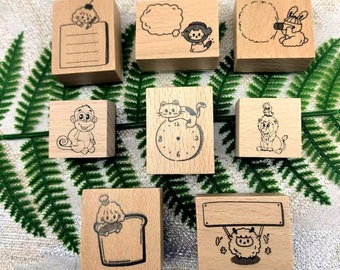 May include: Eight wooden stamps with various designs, including a cat on a clock, a monkey, a lion, a sheep, a cloud, a girl with a cherry, a girl with a bunny, and a dog in a bread loaf.