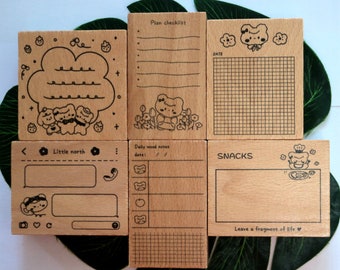 May include: Set of six wooden stamps featuring cute cartoon bears and various designs. The stamps include a checklist, daily mood notes, a phone screen, a grid, and a snack section. Each stamp has a different design and is perfect for adding a touch of whimsy to your planner or journal.