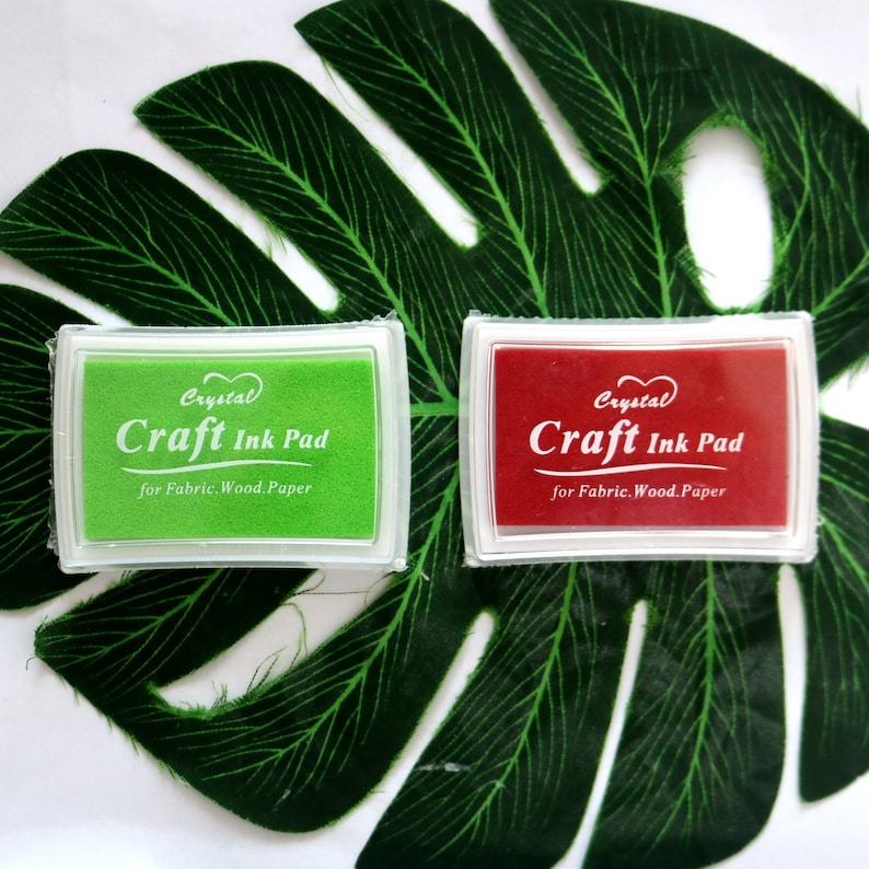May include: Two craft ink pads, one green and one red, with the text "Crystal Craft Ink Pad for Fabric. Wood. Paper" on each.