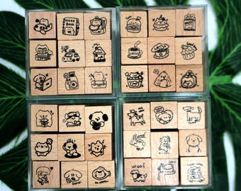 Puede incluir: Un conjunto de 36 sellos de madera en una caja de plástico transparente. Los sellos presentan varias ilustraciones lindas, que incluyen animales, comida y objetos cotidianos. Los sellos están dispuestos en cuatro filas de nueve. La caja tiene una tapa transparente y un fondo blanco.