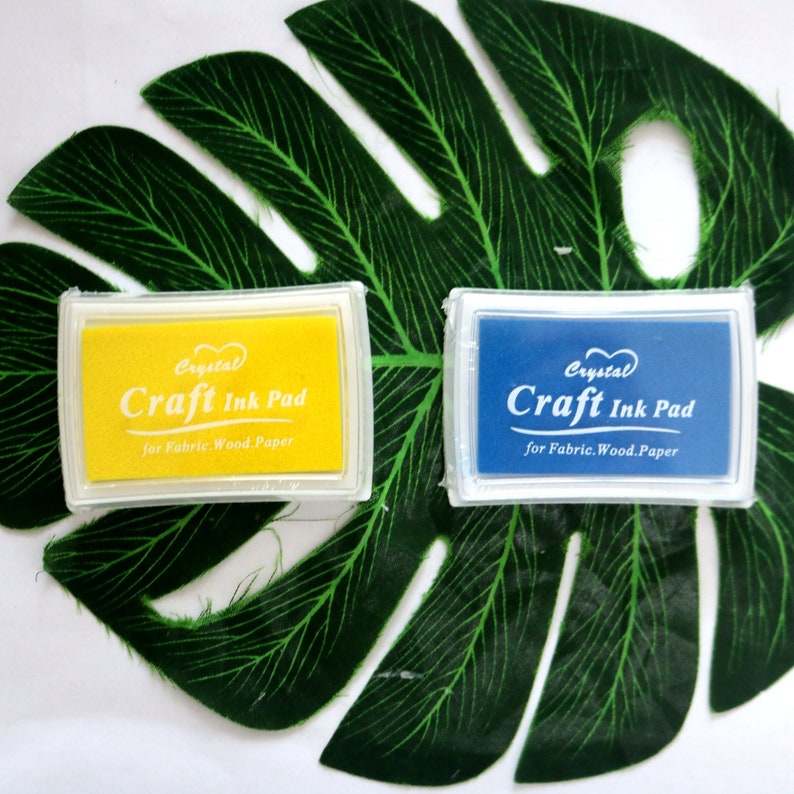 May include: Two craft ink pads, one yellow and one blue, with the text "Crystal Craft Ink Pad for Fabric. Wood. Paper" on each.