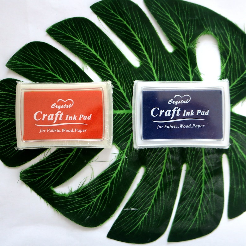 May include: Two craft ink pads, one red and one blue, with the text "Crystal Craft Ink Pad for Fabric. Wood. Paper" on each.