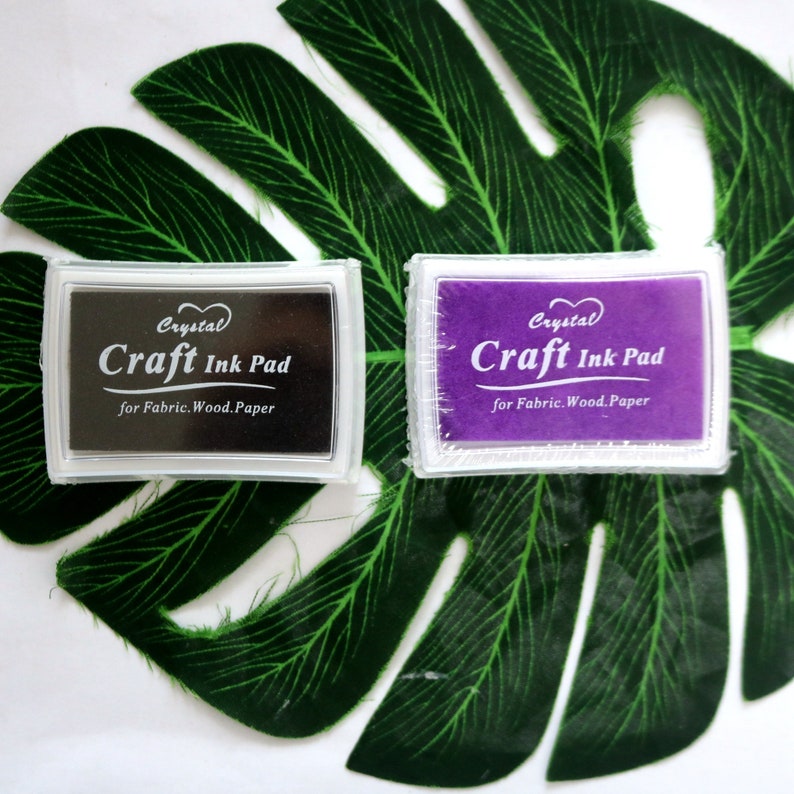 May include: Two craft ink pads, one black and one purple, with the text "Crystal Craft Ink Pad for Fabric. Wood. Paper" on each.