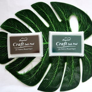 May include: Two craft ink pads, one brown and one green, with the text "Crystal Craft Ink Pad for Fabric. Wood. Paper" on each.