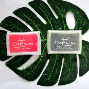 May include: Two craft ink pads, one red and one gray, with the text "Crystal Craft Ink Pad for Fabric. Wood. Paper" on each.