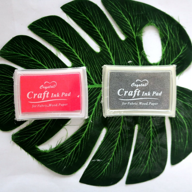 May include: Two craft ink pads, one red and one gray, with the text "Crystal Craft Ink Pad for Fabric. Wood. Paper" on each.