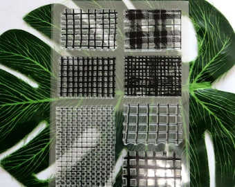 May include: A sheet of clear, transparent stamps with six different black and white grid patterns. The stamps are designed for crafting and scrapbooking.