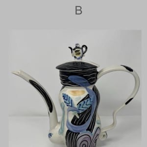 May include: A decorative ceramic teapot with a black, white, and blue design. The teapot features a long spout, a curved handle, and a small teapot on the lid. The body of the teapot is decorated with abstract patterns.