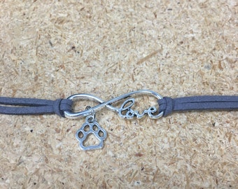 May include: A gray suede bracelet with an infinity symbol charm that says "love" and a paw print charm.