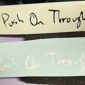 May include: Two versions of a vinyl sticker with the words "Push On Through" written in a handwritten style. The top sticker is black on a white background. The bottom sticker is white on a light blue background.