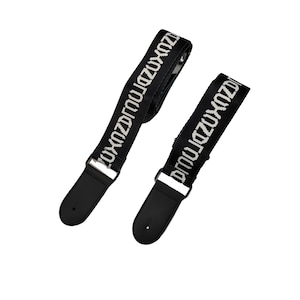 K&ouml;nnte beinhalten: Zwei schwarze Gitarrengurte mit wei&szlig;em Text "ZUXOZDRQ". Jeder Gurt hat ein schwarzes Lederendst&uuml;ck und silberfarbene Metallbeschl&auml;ge. Die Gurte sind vor einem wei&szlig;en Hintergrund abgewinkelt.
