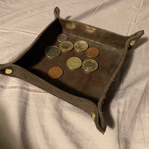 May include: A brown leather tray with a suede interior, holding a collection of British coins.