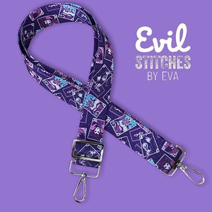 May include: Purple and white adjustable strap with a repeating pattern of cartoon characters. The strap has silver hardware and the text "Evil Stitches by Eva" is printed on a white background.