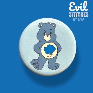 May include: A blue Care Bear button with a grumpy expression, a blue cloud with raindrops, and the text "Evil Stitches by Eva".