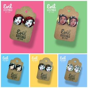 May include: Six pairs of earrings featuring different Disney princesses. Each pair is on a brown card with the text "Evil Stitches by Eva".