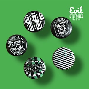 Könnte beinhalten: Fünf schwarze und weiße Anstecknadeln mit verschiedenen Designs. Die Nadeln zeigen den Text "Beetlejuice", "Strange & Unusual", "Never Trust The Living" und "Beetlejuice" in einer stilisierten Schriftart. Eine Nadel hat ein schwarz-weiß gestreiftes Design mit grünen Akzenten.