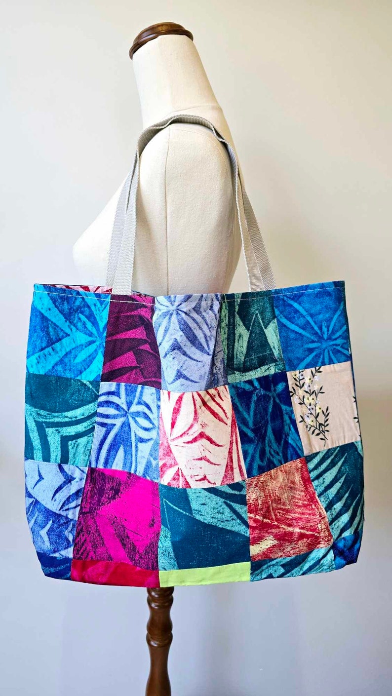 May include: A patchwork tote bag with a variety of blue, pink, green, and white floral patterns. The bag has two white straps.