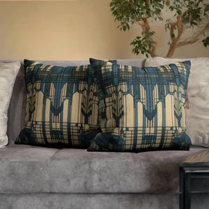 May include: Two square throw cushions featuring a geometric pattern in shades of blue, cream, and dark green. The design consists of vertical lines and angular shapes that create a structured, repeating motif across the fabric surface of both cushions.