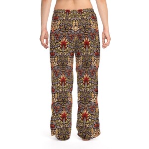 Op de afbeelding: Brede broek met een bloemenpatroon in tinten rood, groen, geel en bruin. Het patroon is een herhalend ontwerp van gestileerde bloemen en bladeren.