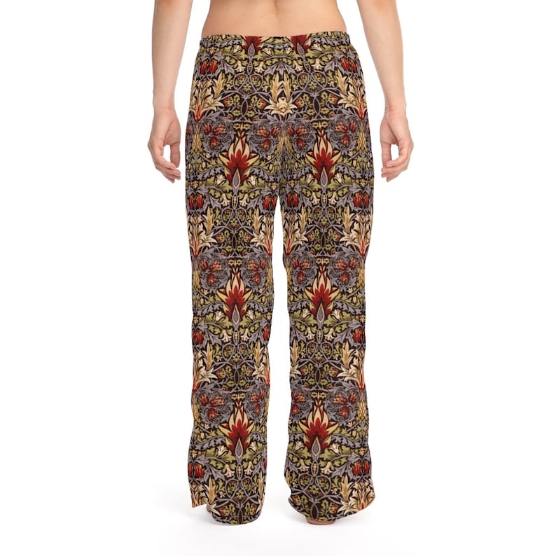 Op de afbeelding: Brede broek met een bloemenpatroon in tinten rood, groen, geel en bruin. Het patroon is een herhalend ontwerp van gestileerde bloemen en bladeren.