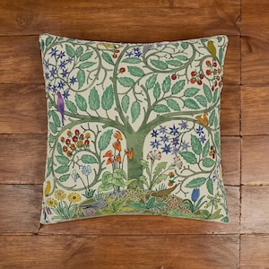 May include: A cream-colored throw pillow with a green tree of life design. The tree is surrounded by colorful flowers, birds, and berries.