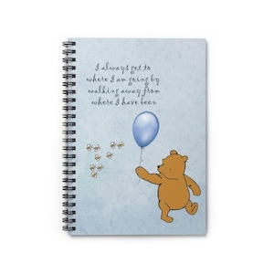Puede incluir: Una libreta de espiral azul con una ilustración de Winnie de Pooh. La libreta presenta una cita de Winnie de Pooh: "Siempre llego a donde voy caminando lejos de donde he estado."