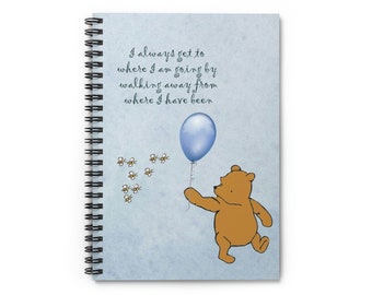 May include: A blue spiral bound notebook with a Winnie the Pooh illustration. The notebook features a quote from Winnie the Pooh: "I always get to where I am going by walking away from where I have been."