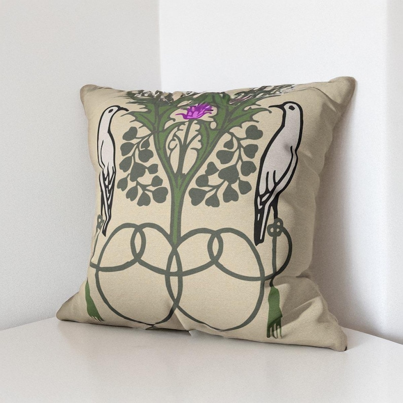 Pu&ograve; includere: Un cuscino quadrato con sfondo beige caratterizzato da un'illustrazione grafica di due uccelli bianchi appollaiati su steli verdi intrecciati. Una pianta verde centrale con un fiore viola si trova tra gli uccelli, con nappe verdi.