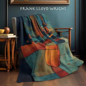 May include: A throw blanket with an abstract geometric design in shades of blue, orange, and teal, draped over a chair. The text "FRANK LLOYD WRIGHT" is visible at the top. The blanket's design features rectangular and curved shapes.