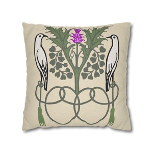 Pu&ograve; includere: Un cuscino quadrato con sfondo beige caratterizzato da una stampa grafica simmetrica. Il design include due uccelli bianchi rivolti verso l'esterno, appollaiati su elementi decorativi verdi simili a corde con nappe, che fiancheggiano un cardo viola.