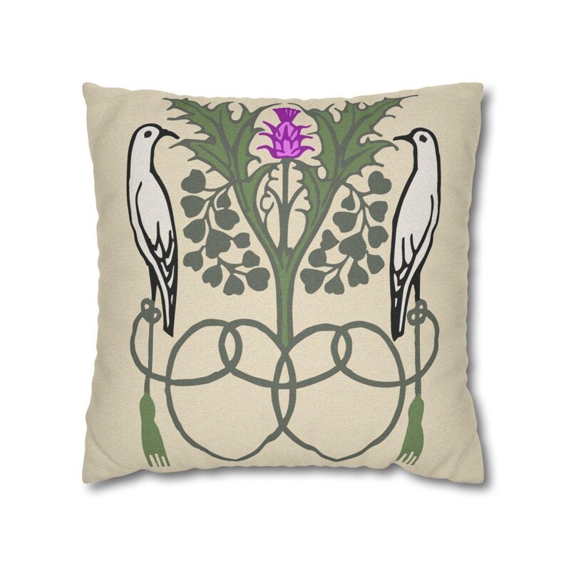 Pu&ograve; includere: Un cuscino quadrato con sfondo beige caratterizzato da una stampa grafica simmetrica. Il design include due uccelli bianchi rivolti verso l'esterno, appollaiati su elementi decorativi verdi simili a corde con nappe, che fiancheggiano un cardo viola.