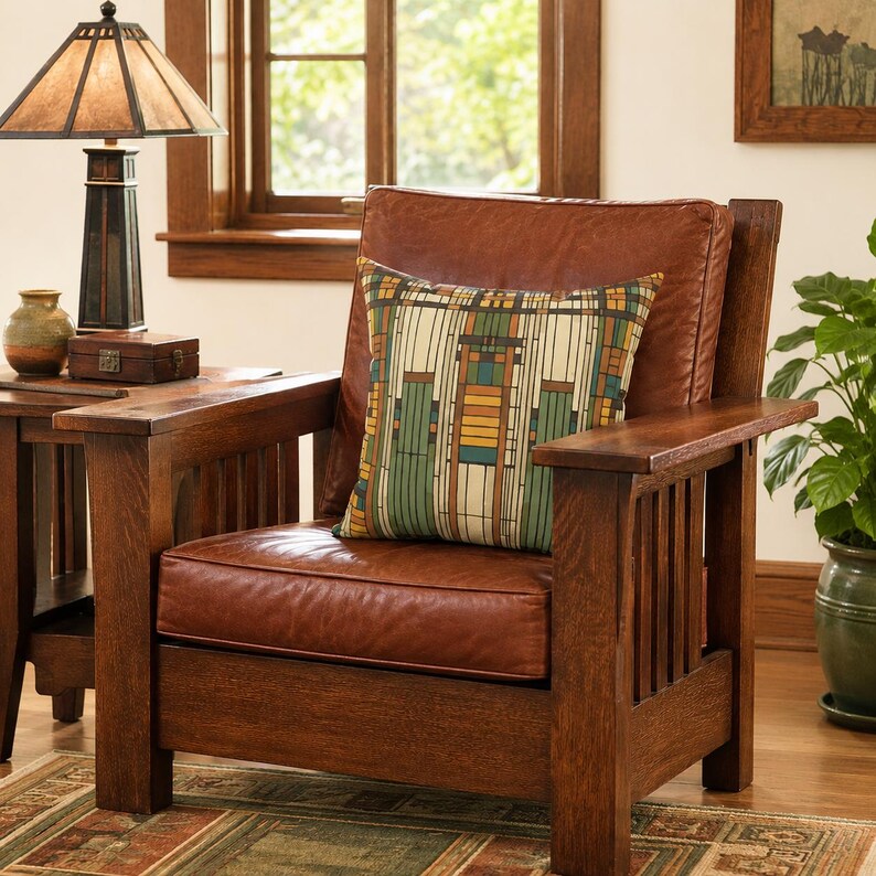 May include: A brown leather armchair with a wooden frame and vertical slat sides. A square throw pillow rests on the seat, featuring a geometric pattern in shades of green, yellow, and brown. The chair has a thick back cushion and a seat cushion.
