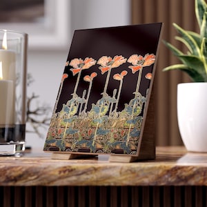 May include: A black tile with a decorative design of orange poppies on black stems with green leaves. The tile has a gold border with a repeating pattern of blue, green, and gold leaves. The tile is on a wooden stand.