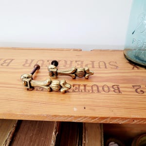 Könnte beinhalten: Ein Set aus drei Keramikbechern mit gesprenkelter, matter Oberfläche. Die Becher sind in den Farbtönen Creme, Hellgrau und Dunkelgrau gehalten. Jeder Becher hat ein schlichtes, minimalistisches Design und einen abgerundeten Henkel. Die Becher sind aufeinander gestapelt.