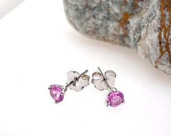 Pode incluir: Um par de brincos de prata com pedras preciosas cor-de-rosa. Os brincos têm um design simples e são perfeitos para o uso diário.
