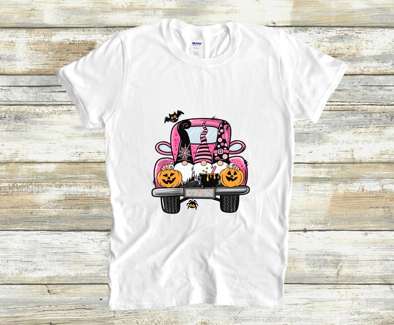 May include: Three gnomes in a pink pickup truck with pumpkins and a cauldron. The gnomes are wearing witch hats and have black beards. The truck has black wheels and a black spider on the back.