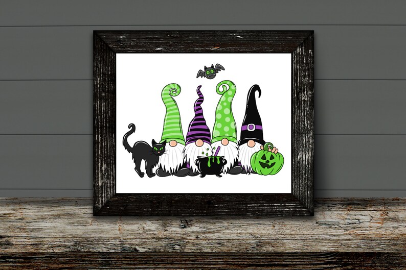 May include: A framed Halloween-themed print featuring five cartoon gnomes with green and purple hats, a black cat, a cauldron, a green pumpkin, and a bat. The gnomes have white beards and are set against a white background.