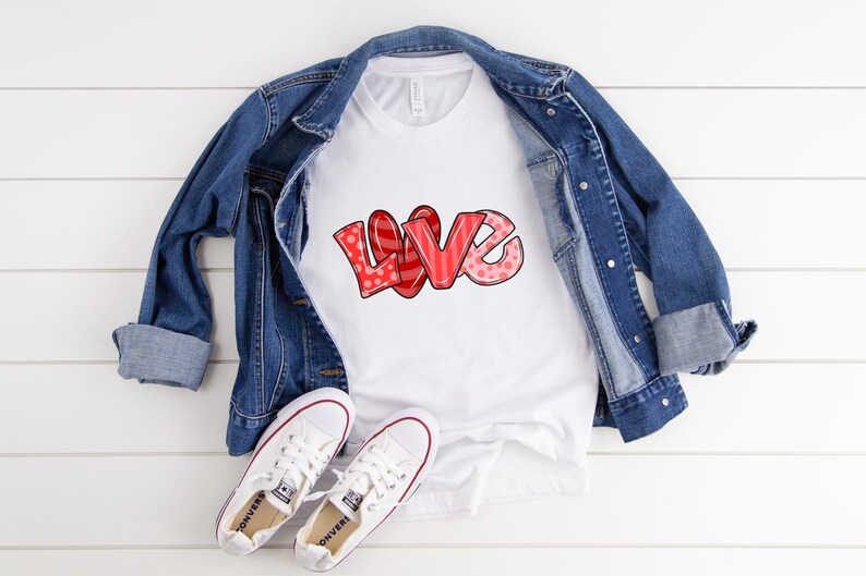 以下が含まれることがあります： 赤とピンクのデザインで「LOVE」という文字が入った白いTシャツ、デニムジャケットと白いスニーカーを組み合わせたもの。「LOVE」という文字は、水玉模様とストライプが入ったバブルレタースタイルです。