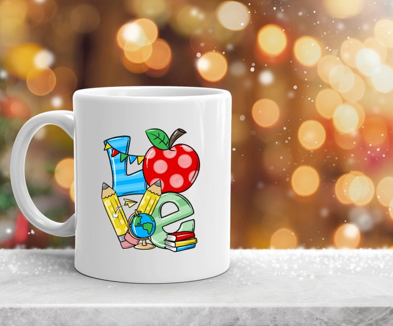May include: White ceramic mug with a colorful illustration of the word "LOVE" made up of school supplies, including pencils, a globe, and a red apple.
