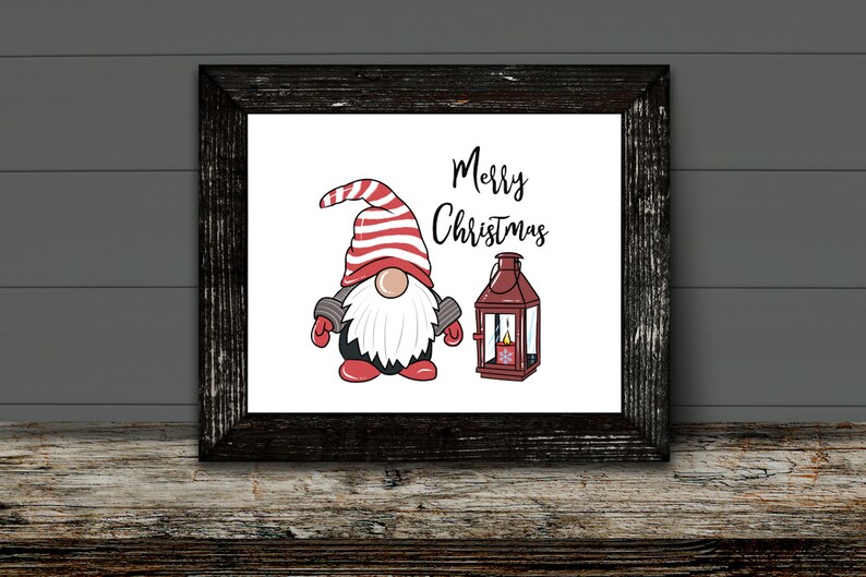 May include: A framed print featuring a Christmas gnome with a red and white striped hat, a white beard, and red mittens. Beside the gnome is a red lantern with a lit candle. The words "Merry Christmas" are written above the gnome.